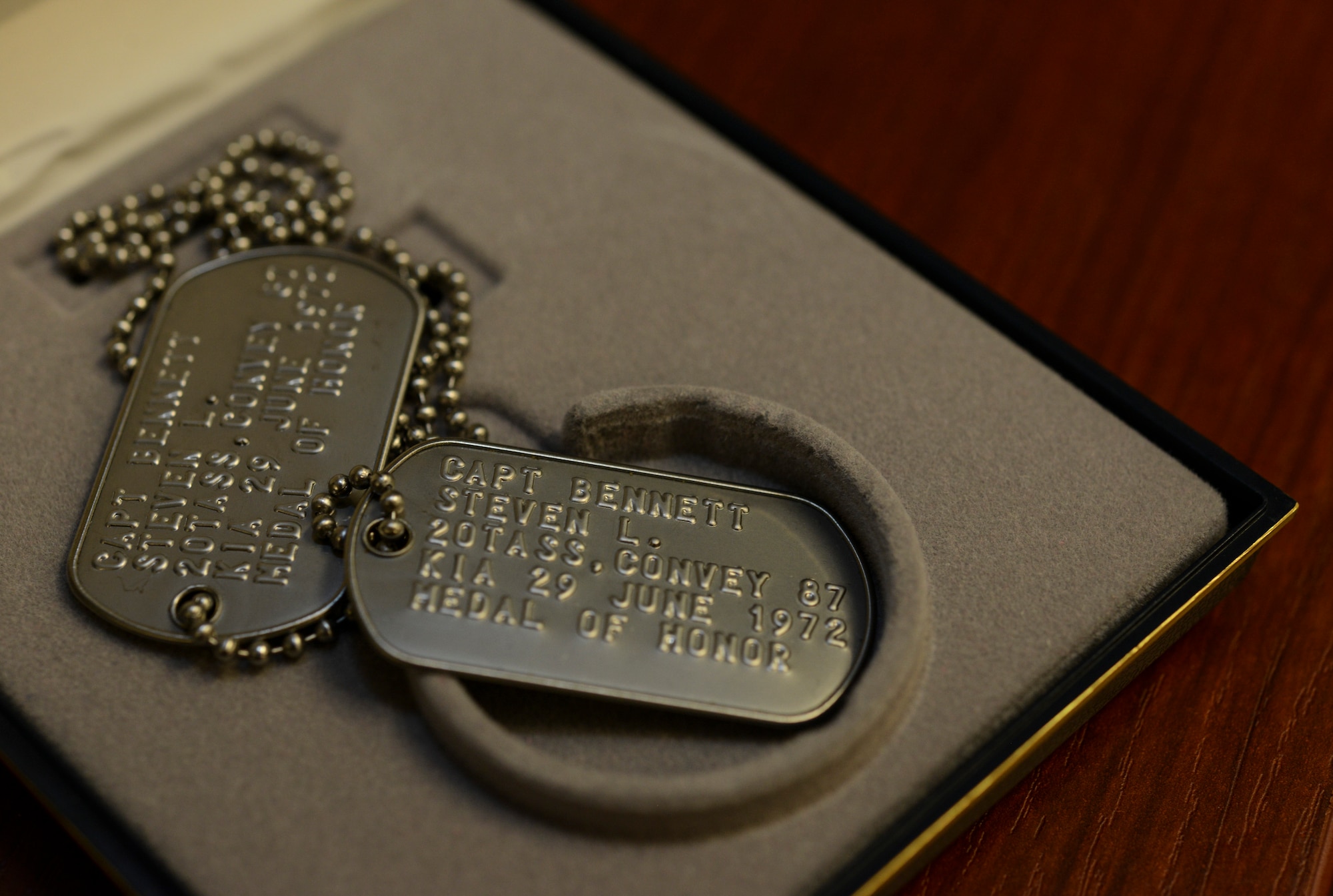 One pair of dog tags sitting in a box on a desk.