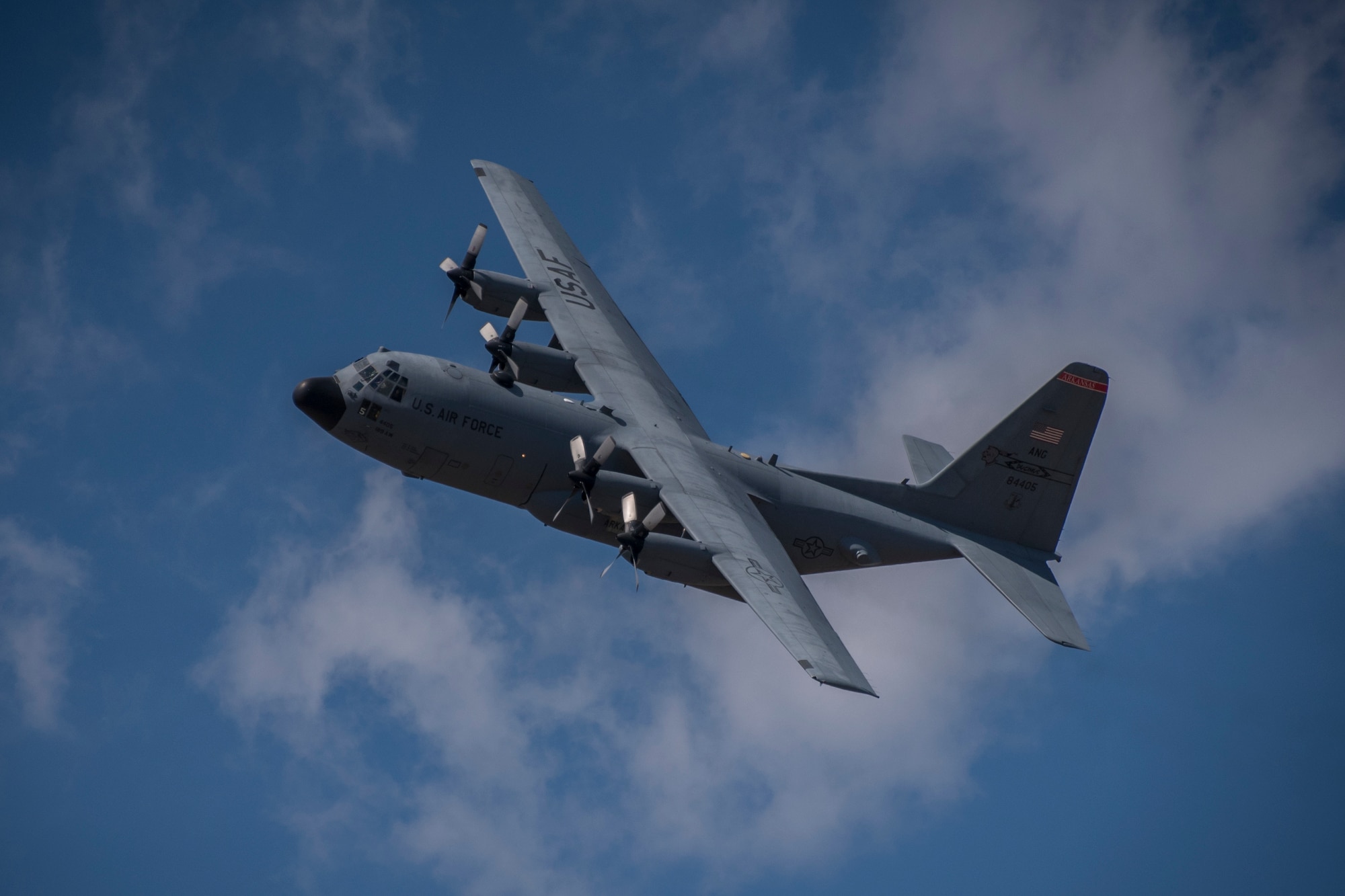 A photo of a C-130 flying against a blue sky.