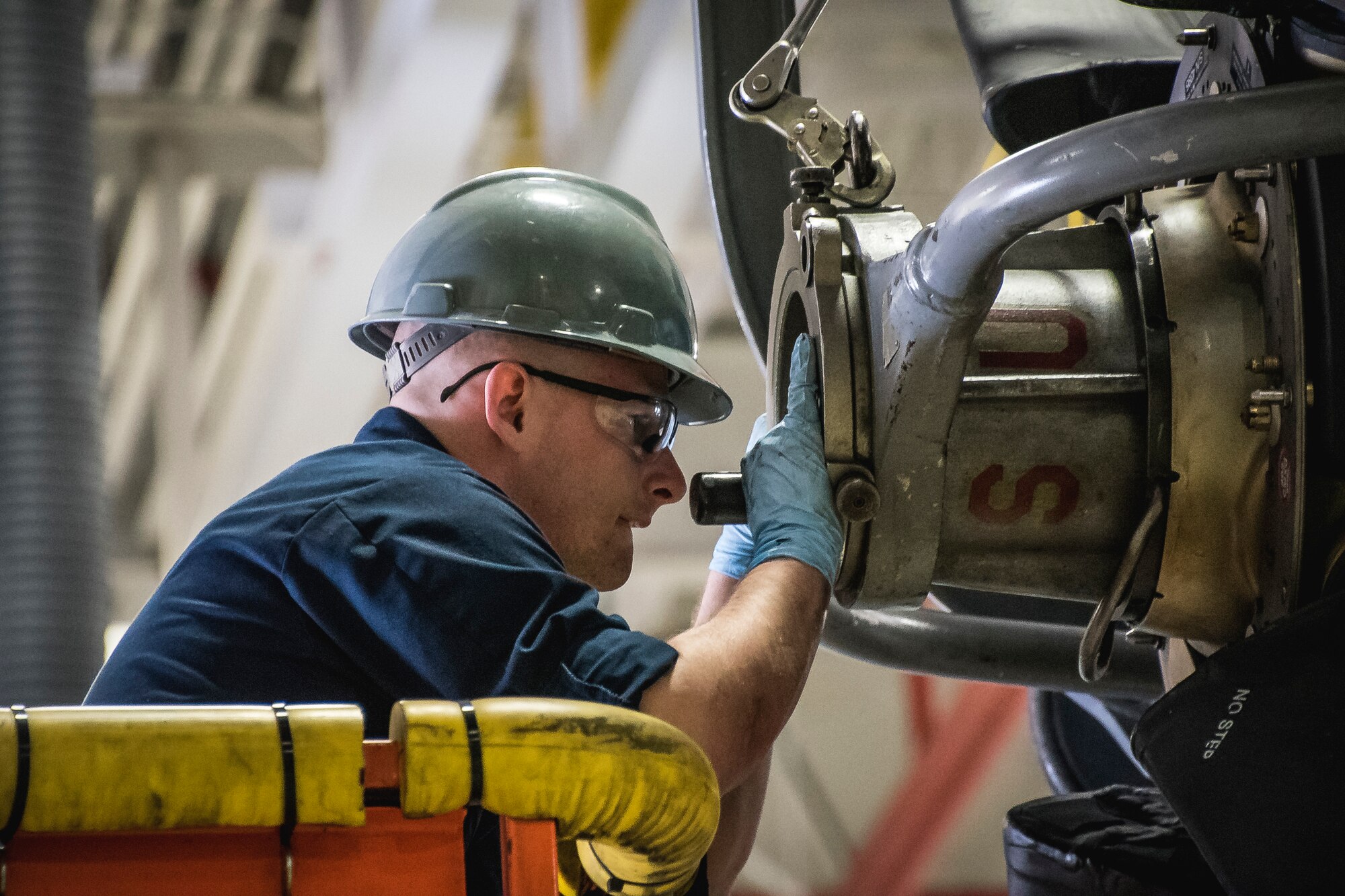 Photo of a military member working on an aircraft engine.