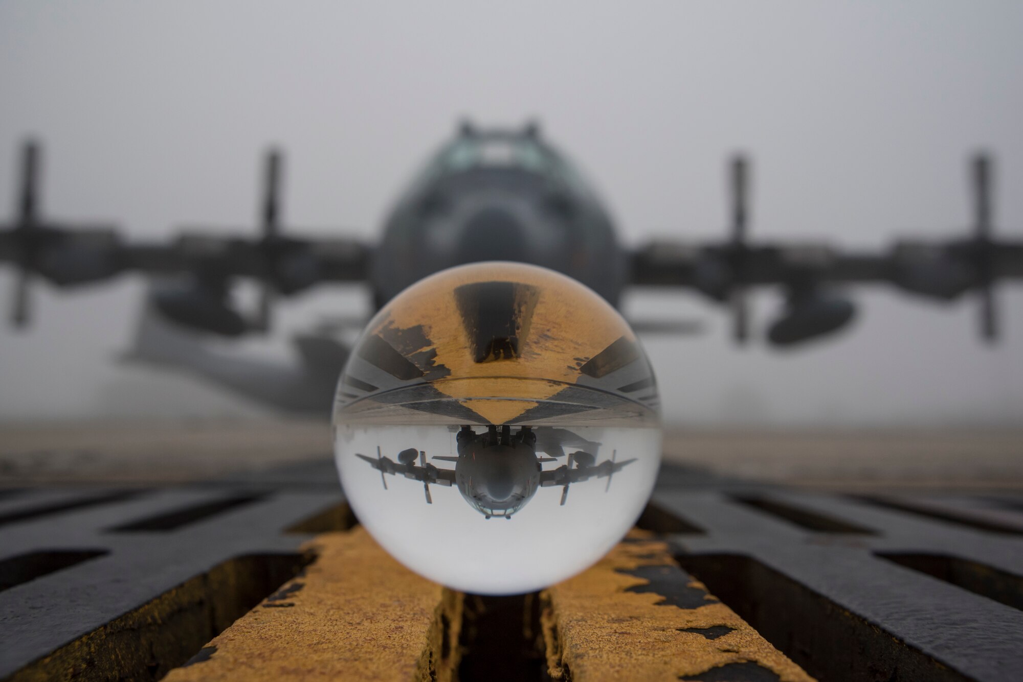 Abstract photo of a glass ball reflecting a C-130's upside-down image on the flight line.
