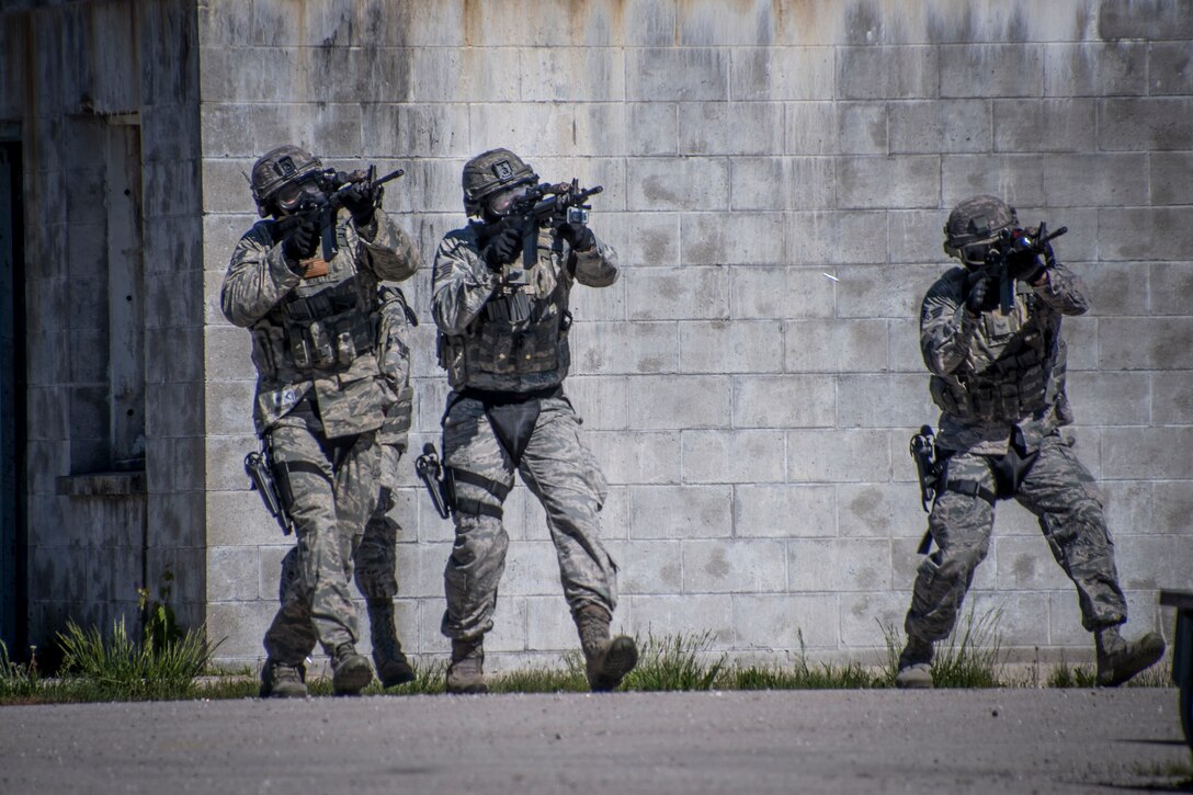 Photo of 3 military members aiming weapons.