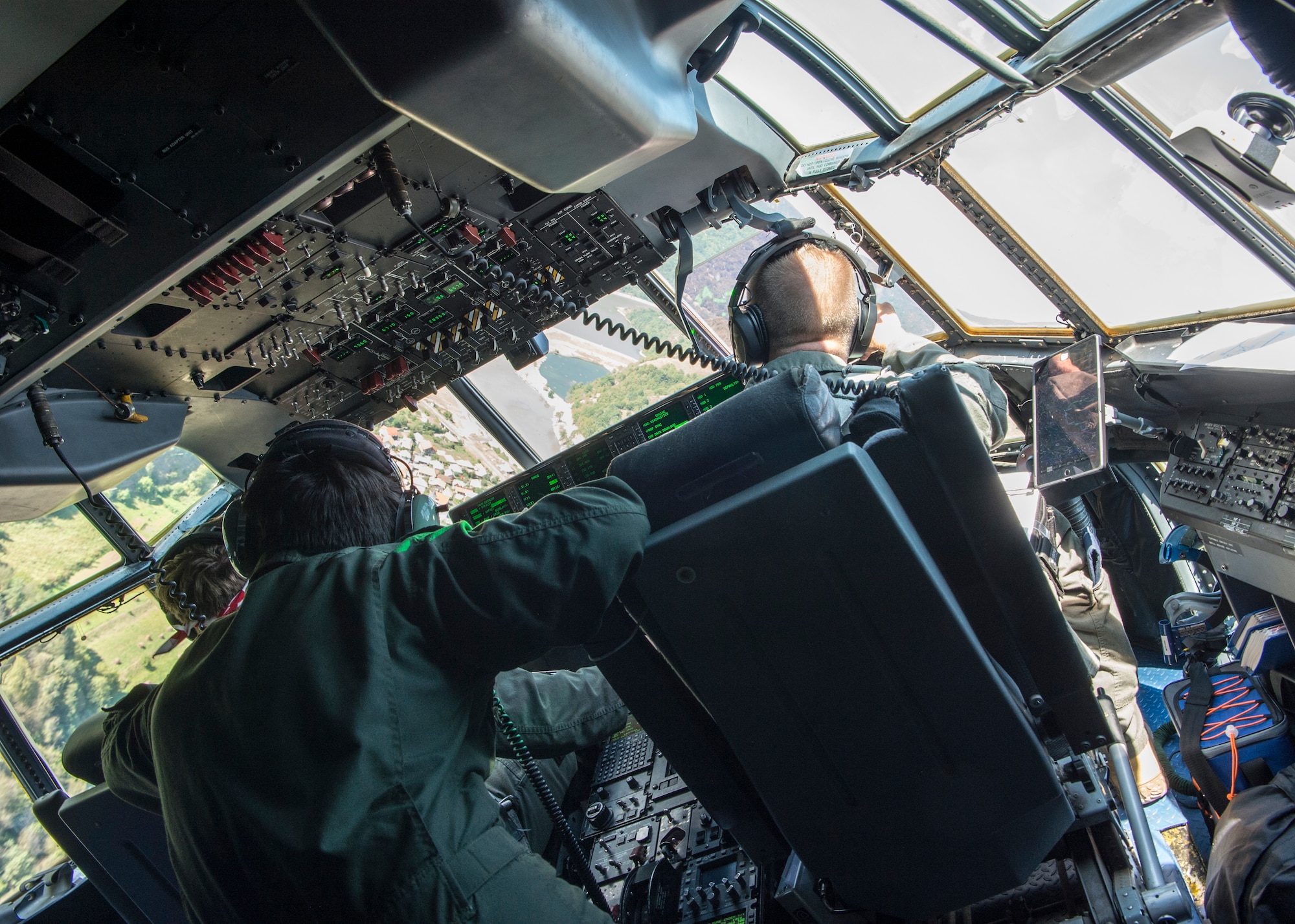 Romanian and U.S. Air Force members look out the windshield of a C-130J Super Hercules while flying over Romania, Aug.21, 2019. U.S. military members enhanced readiness and strengthened their relationship with Romania throughout exercise Carpathian Fall 2019. (U.S. Air Force photo by Staff Sgt. Kirby Turbak)