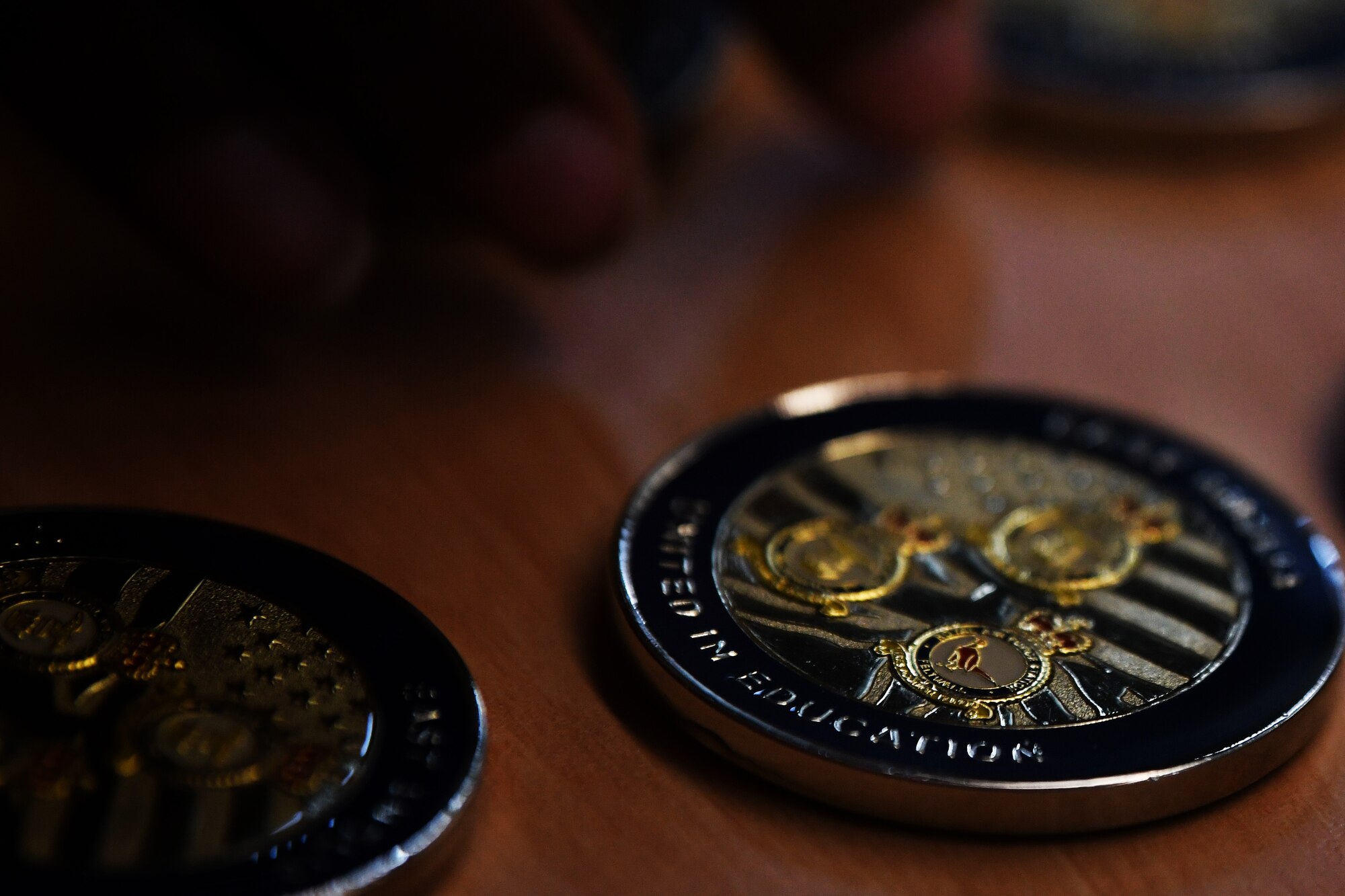 Educator coins are displayed during the annual teacher’s forum at Royal Air Force Lakenheath, England, Aug. 29, 2019. Wing leadership had the opportunity to welcome new educators to RAF Lakenheath and RAF Feltwell and share tri-base updates, congratulatory remarks, and execute a coining ceremony to commemorate their induction into the Liberty Wing family. (U.S. Air Force photo by Airman 1st Class Shanice Williams-Jones)