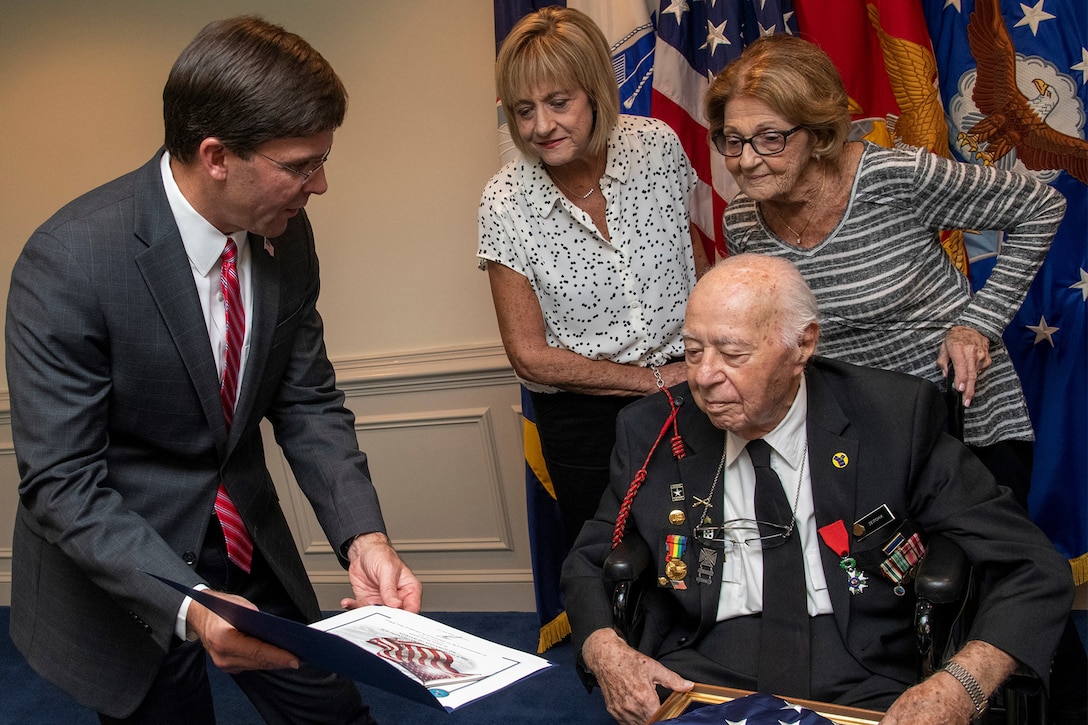 A man presents a war veteran with a certificate.