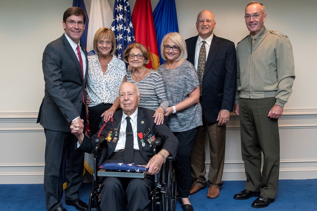 People pose for a photo in front of flags.