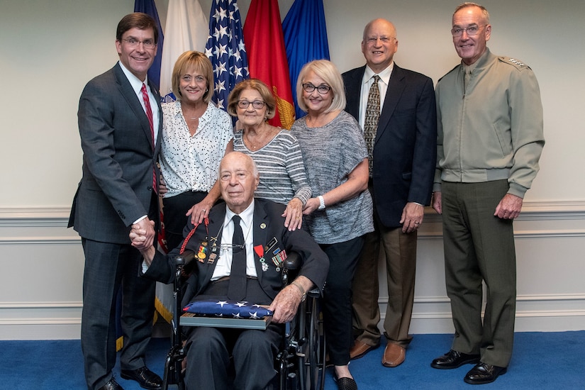 People pose for a photo in front of flags.