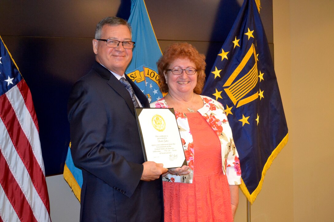 Defense Logistics Agency Troop Support Deputy Commander Richard Ellis, left, presents new retiree Linda Gruber with a certificate upon her retirement from the agency during a ceremony on Aug. 29, 2019 in Philadelphia. She retired after 38 years of service to the agency.