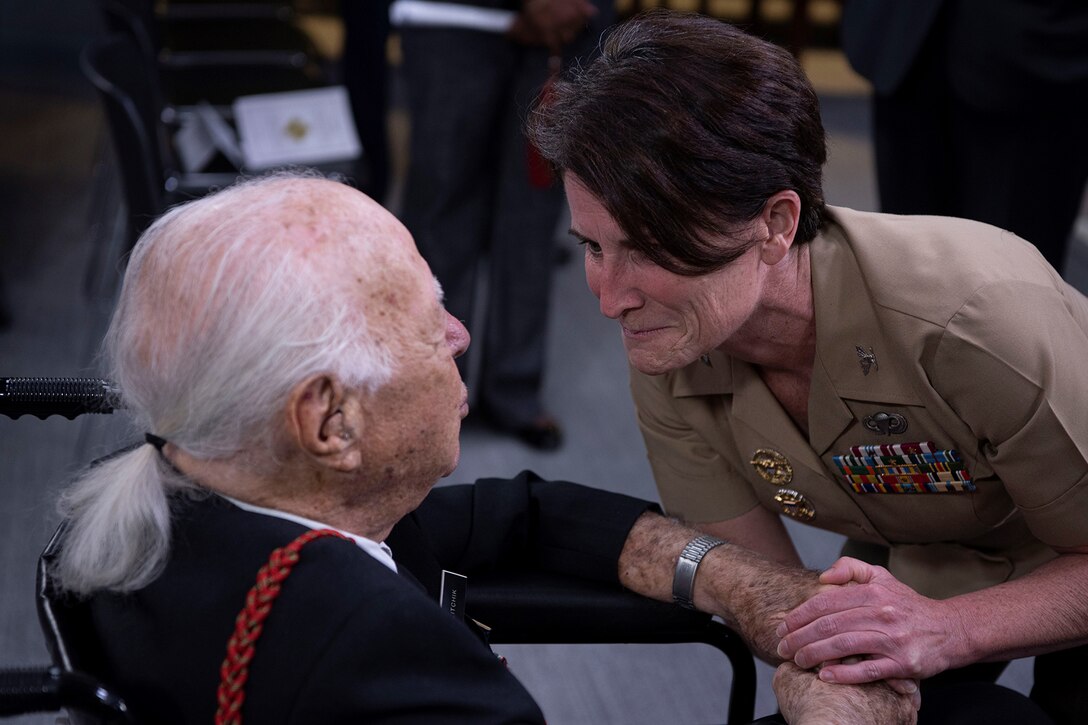 A man in a wheelchair is greeted by a woman in a military uniform.