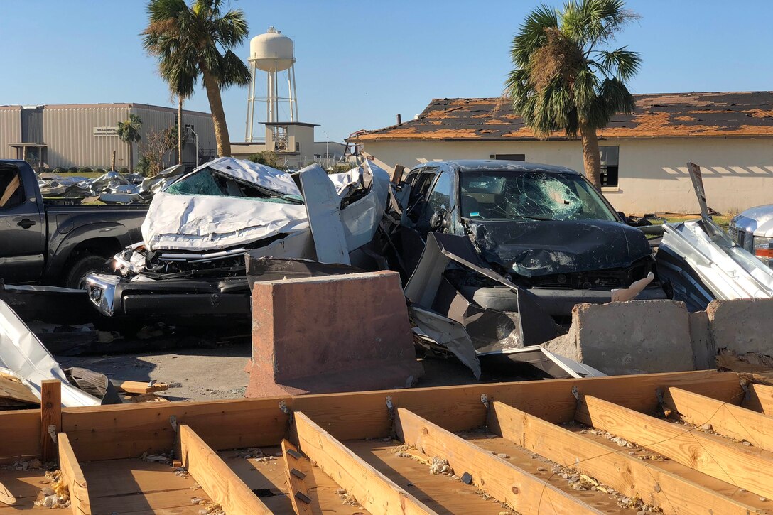 Mangled cars next to a destroyed building.
