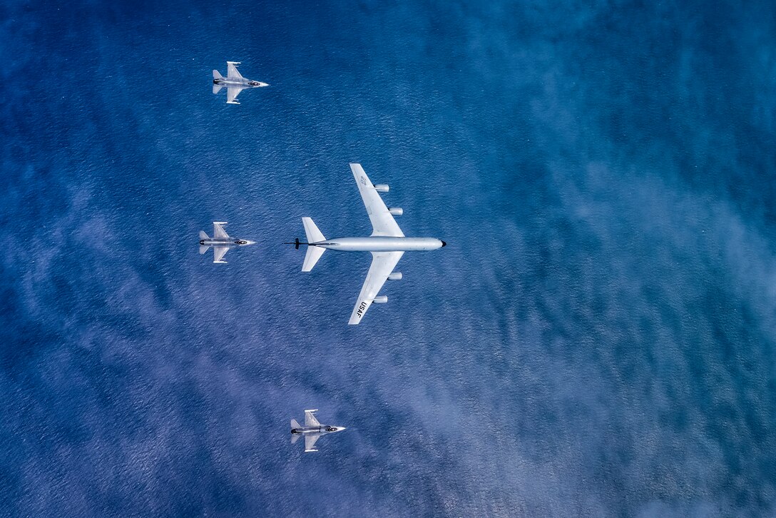 A picture of an aerial view of a KC-135 Stratotanker military refueling aircraft from the 108th Wing and three 177th Fighter Wing F-16C Fighting Falcons.