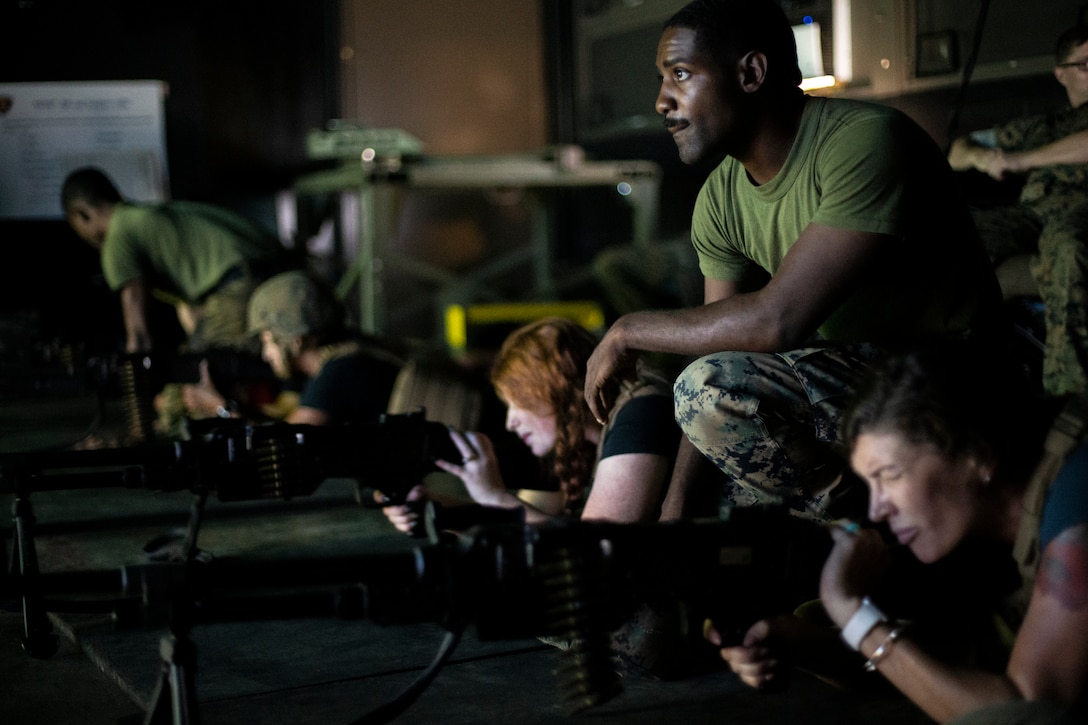 Spouses of Marines from across Marine Corps Air Station Kaneohe Bay operate several weapon systems at an indoor simulated marksmanship trainer during Marine Unmanned Aerial Vehicle Squadron (VMU) 3's In Your Boots Day, Marine Corps Base Hawaii, Aug. 23, 2019. VMU-3's In Your Boots Day gave spouses the opportunity to see the equipment Marines with the unit utilize and engage in some of the physical training they do. (U.S. Marine Corps Photo by Sgt. Alex Kouns)