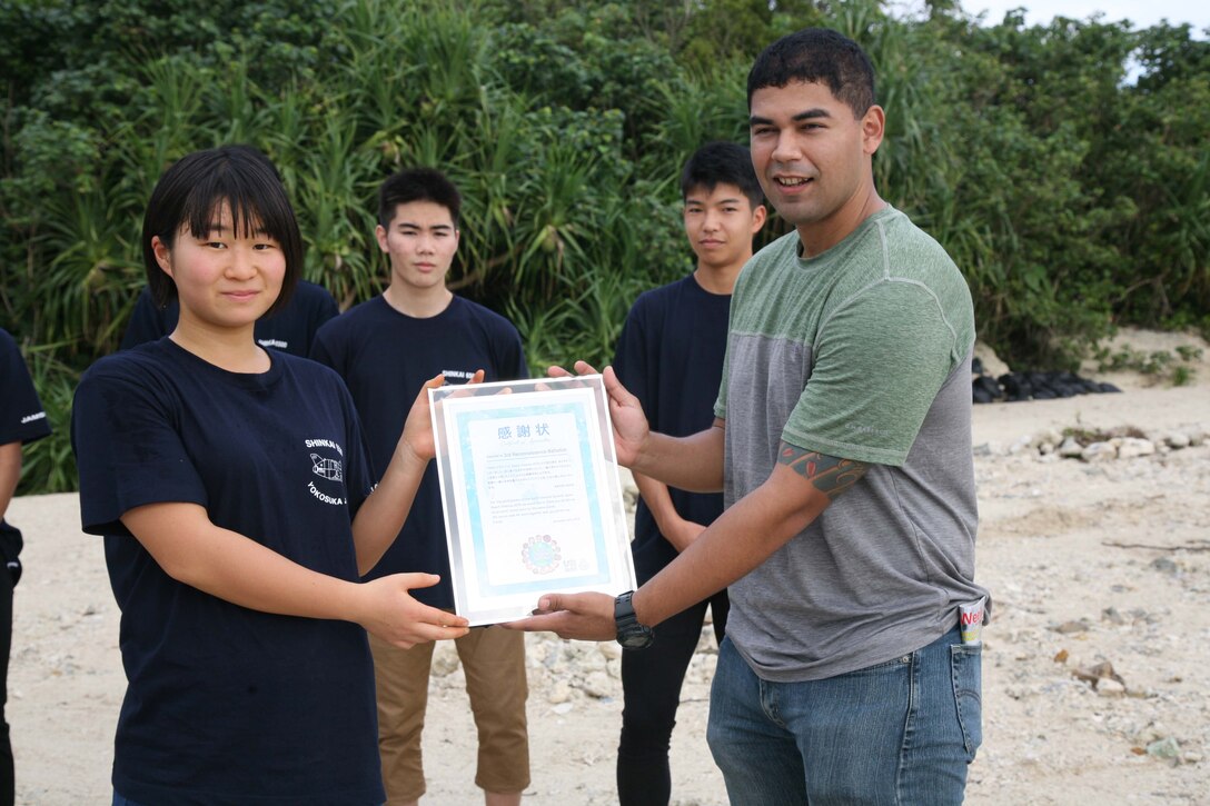 Petty Officer 2nd Class Filberto Noriega receives a letter of appreciation from a high school student from Iwate prefecture Nov. 24, 2019 at Henoko beach. High school students from all over Japan concerning the problem of marine plastic waste visited Camp Schwab to join the Marines of Camp Schwab’s Single Marine Program in cleaning Henoko beach. After the beach cleanup, the students presented a certificate of appreciation to Marines who regularly participate beach cleanups in all over Okinawa.