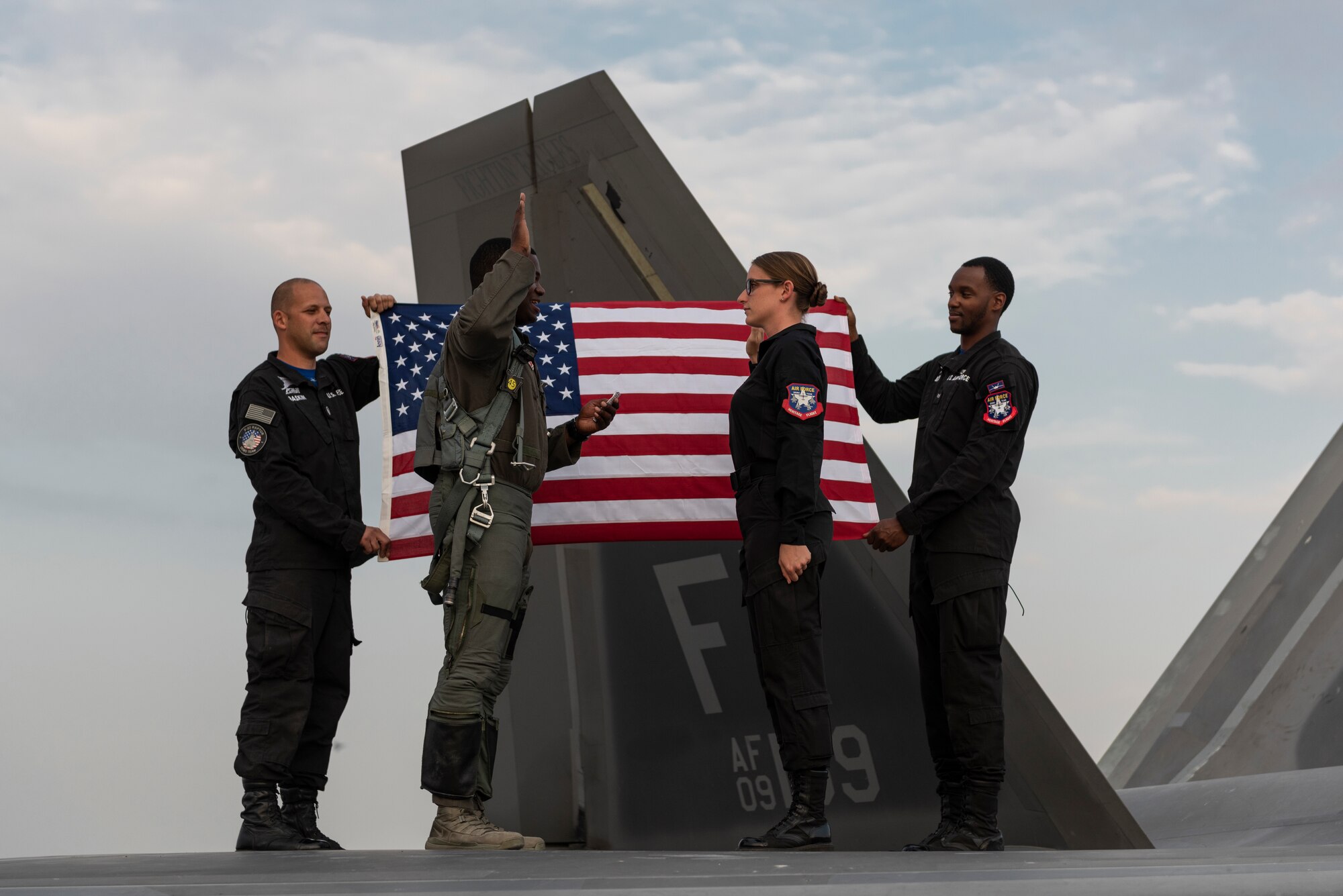 U.S. Air Force Lt. Col. Paul Lopez, second from left, the F-22 Demonstration Team commander, officiates a reenlistment ceremony for U.S. Air Force Staff Sgt. Annemarie Prozzillo, an F-22 Demonstration Team aircrew flight equipment technician, at the Dubai Airshow, United Arab Emirates, Nov. 18, 2019.