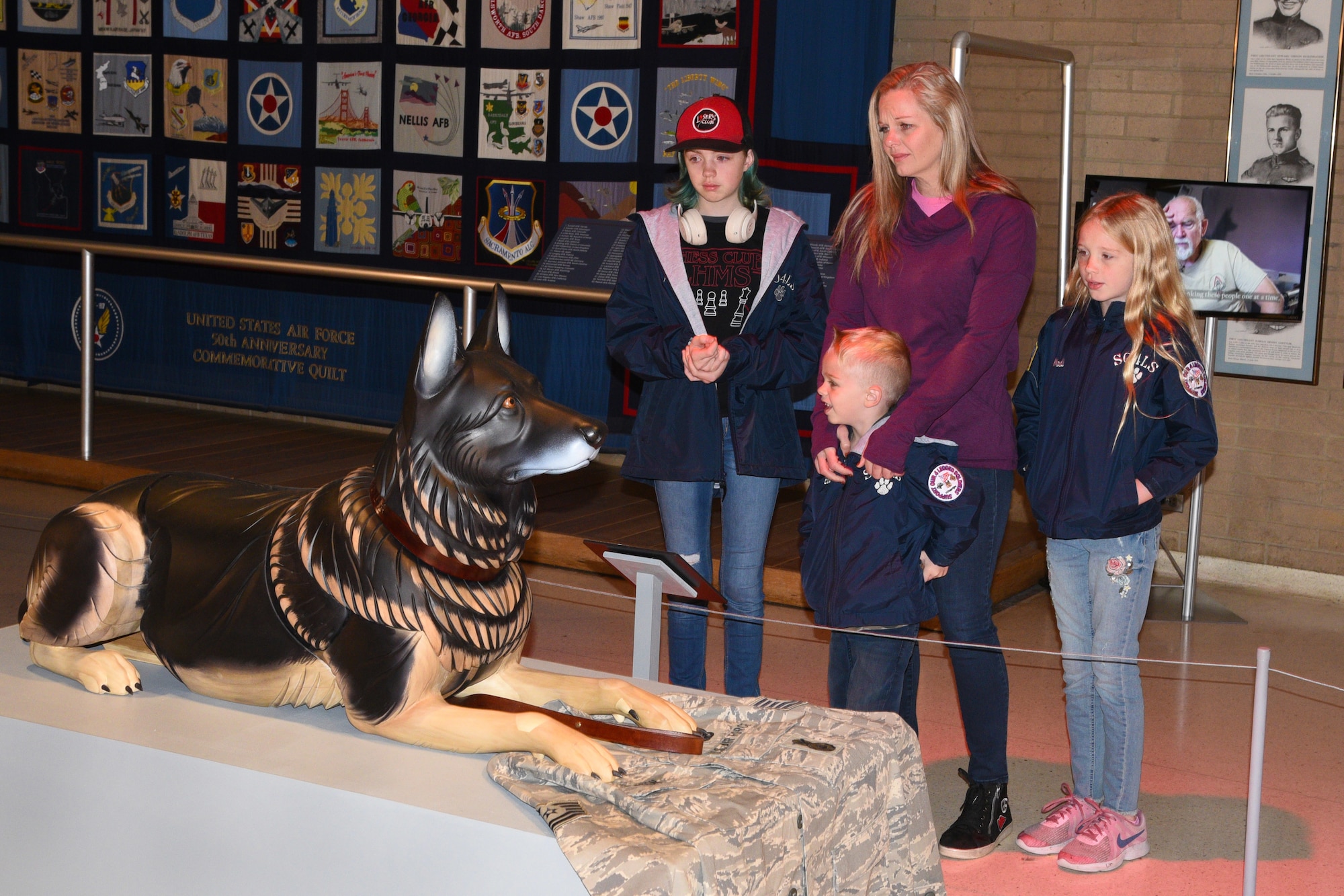 Erin Simpson and family stand with wooden sculpture of their dog Robson at the National Museum of the USAF.