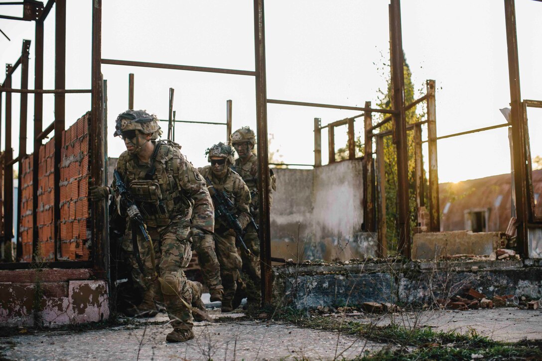 Soldiers run through a damaged building.