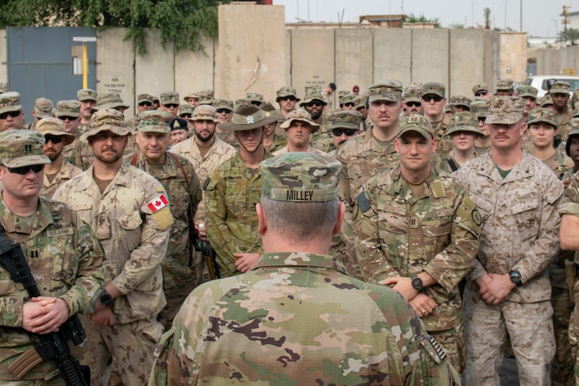 Man in camouflage speaks to hundreds in camouflage.