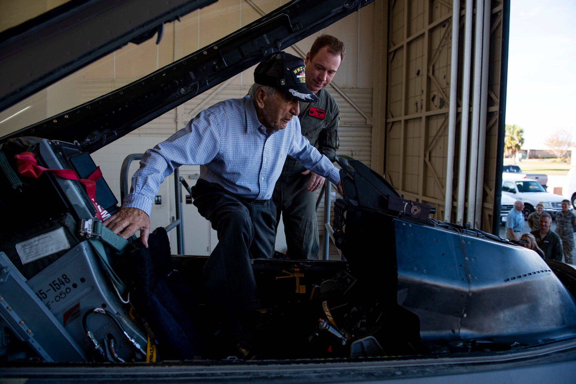 Retired U.S. Air Force Lt. Col. Daniel Daube, left, boards the cockpit of a static QF-16 Fighting Falcon, assisted by U.S. Air Force Lt. Col. Richard Wilson, 325th Operations Support Squadron assistant director of operations, right, at Tyndall Air Force Base, Florida, Nov. 27, 2019. Daube was a veteran of World War II, Korean, and Vietnam war, flying multiple air frames and combat missions. (U.S. Air Force photo by Staff Sgt. Magen M. Reeves)