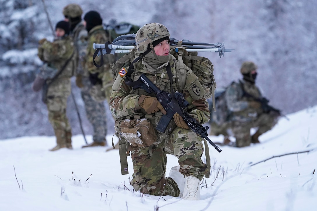 A soldier kneels in snow holding a weapon.