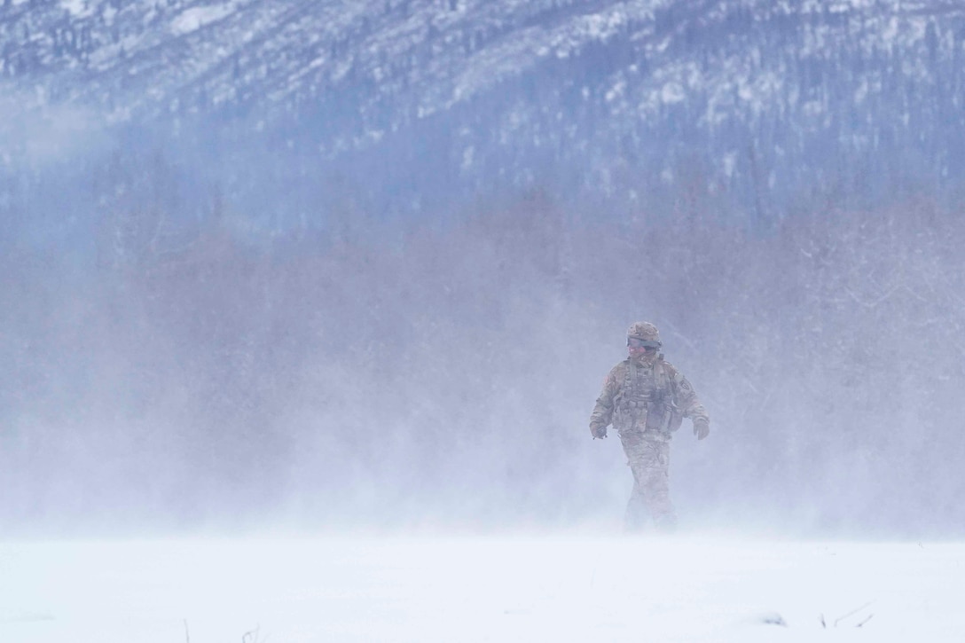 A soldier walks through mist.