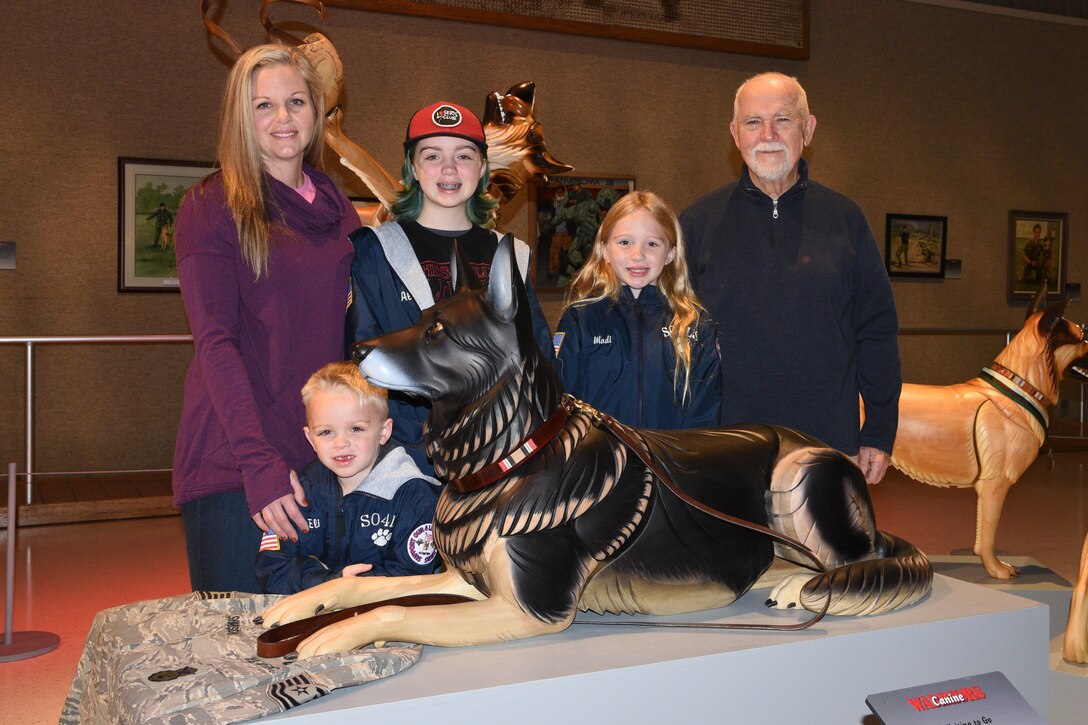 Erin Simpson and family stand with wooden sculpture of their dog Robson at the National Museum of the USAF.