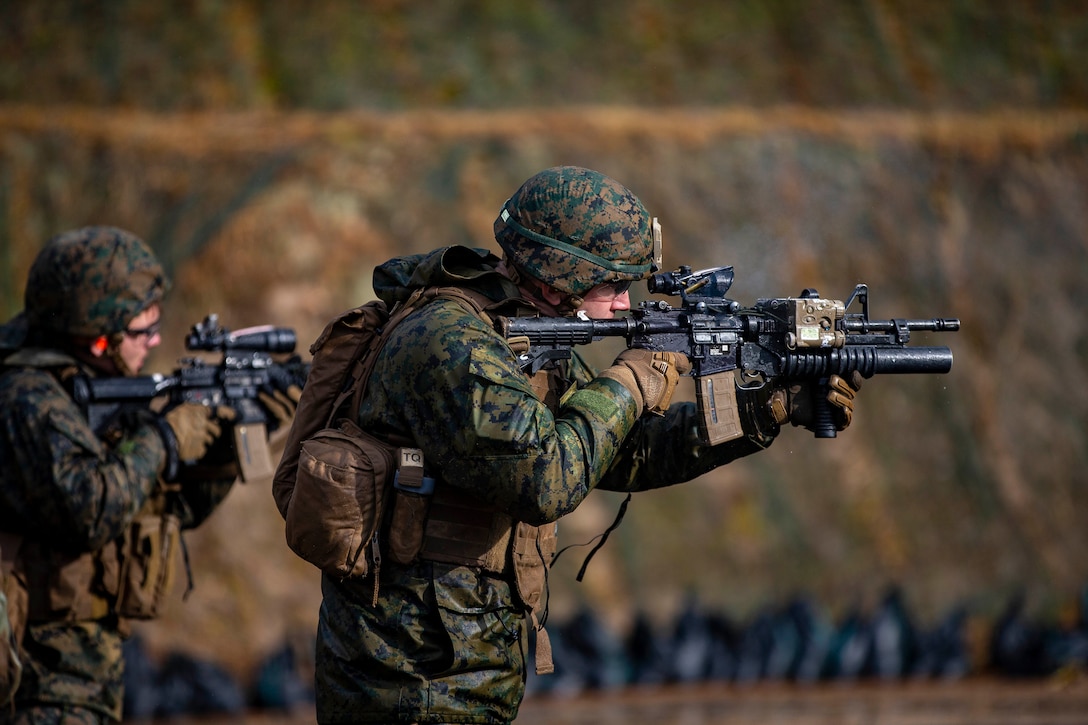 Two Marines aim their weapons at targets.