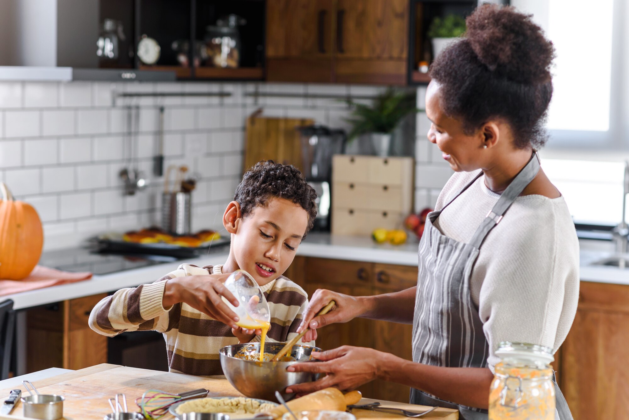 Photo shows mother and son preparing a pie.