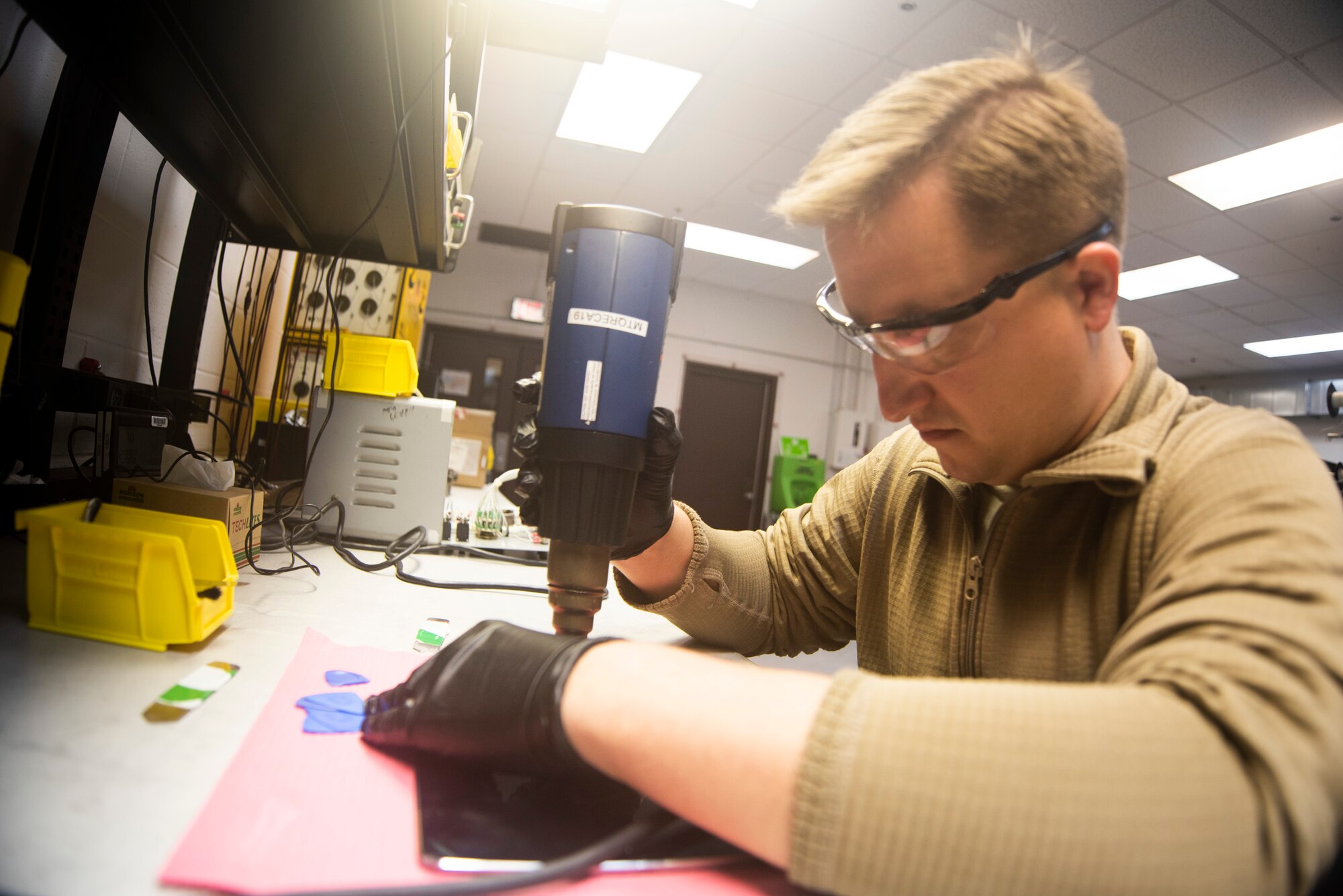 A photo of an Airman heating up adhesive for electronics repair