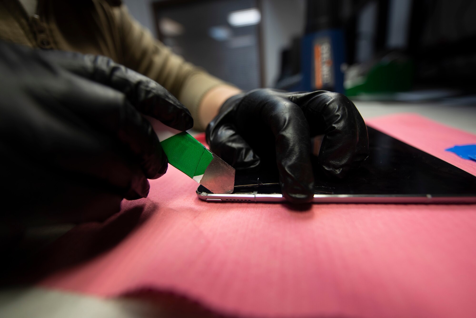 A photo of an Airman removing a tablet screen for repair