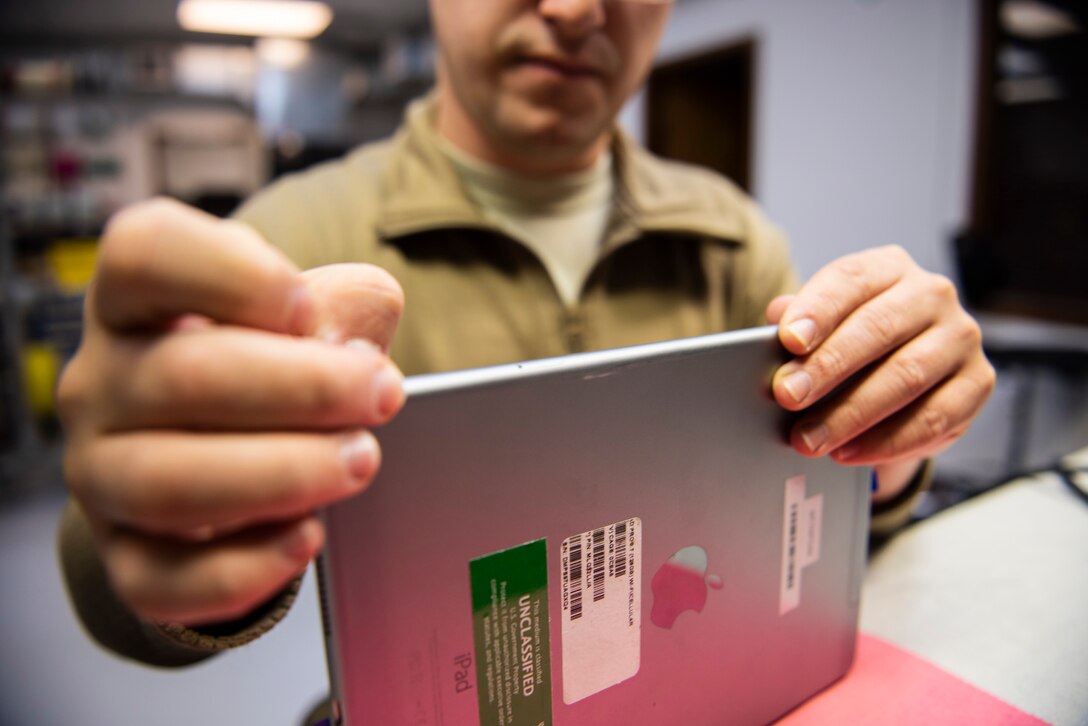 A photo of an Airman installing a new tablet screen after repair