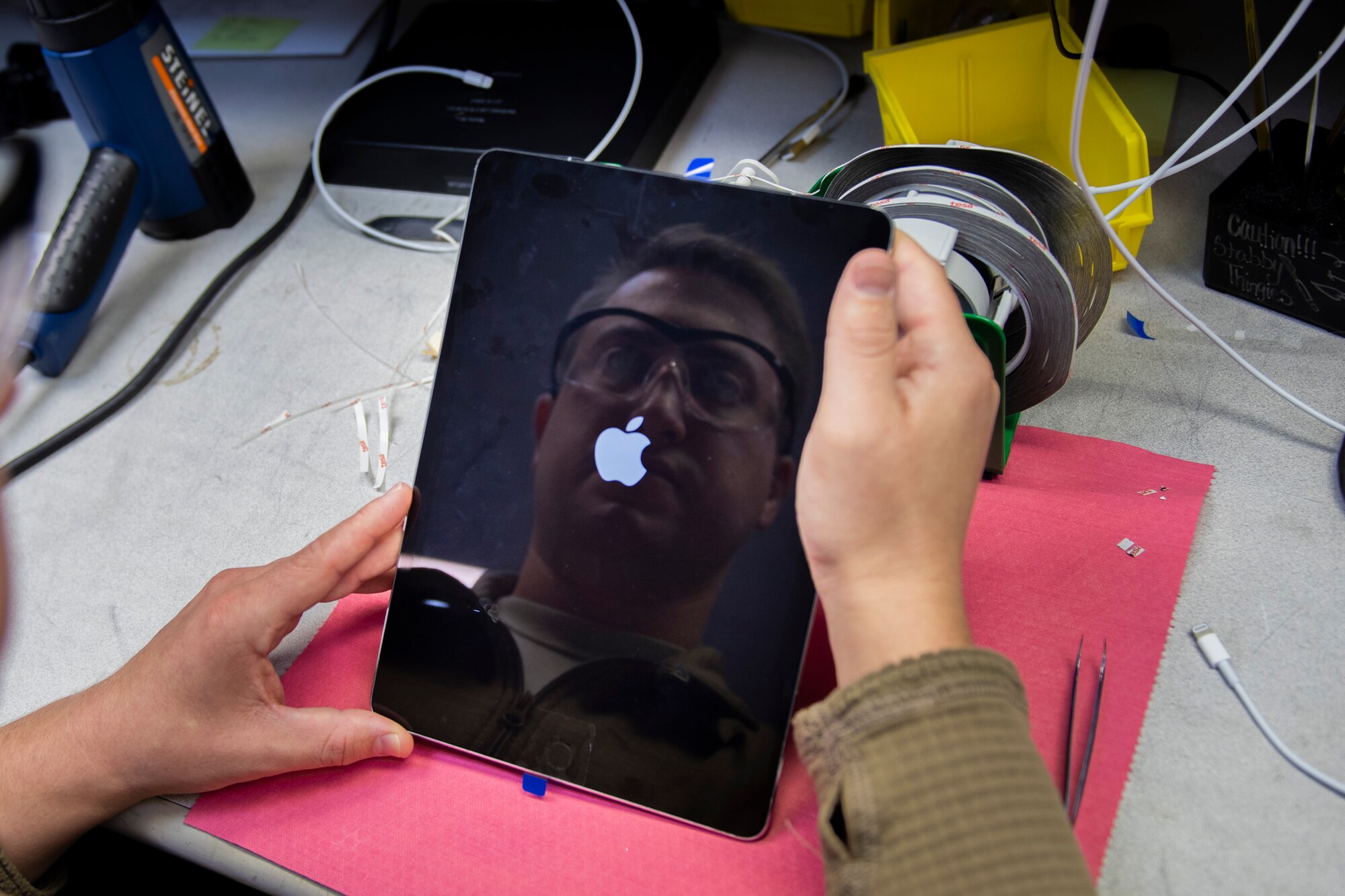 A photo of an Airman testing a new tablet screen after repair