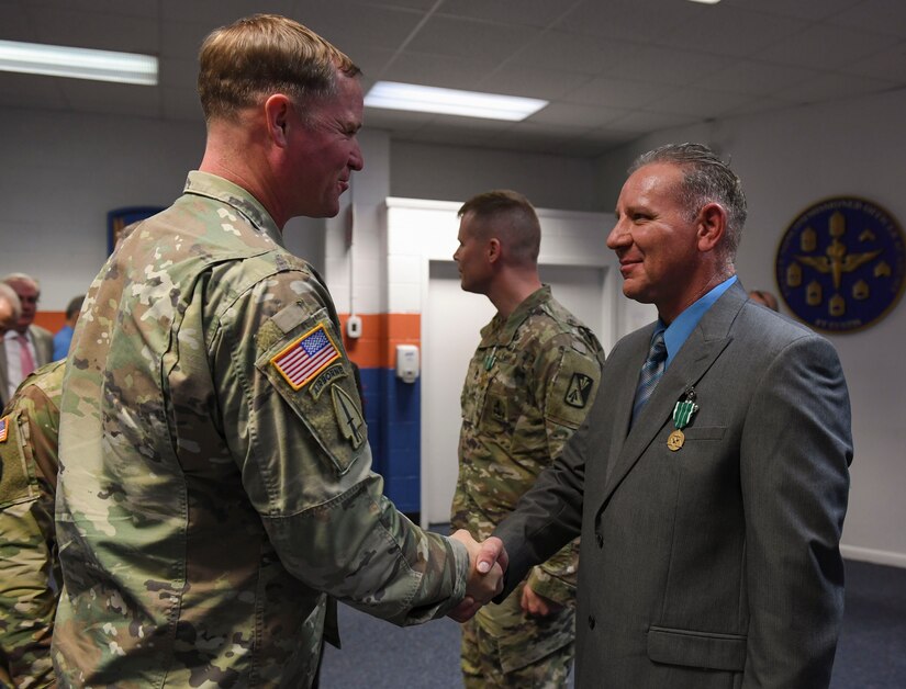U.S. Army Col. Bryan Morgan, 128th Aviation Brigade commander, congratulates William M. Storrs, Charlie Company, 1st Battalion, 210th Aviation Regiment, 128th Aviation Bde. instructor writer, during the Instructor of the Year ceremony at Joint Base Langley-Eustis, Virginia, Nov. 21, 2019.