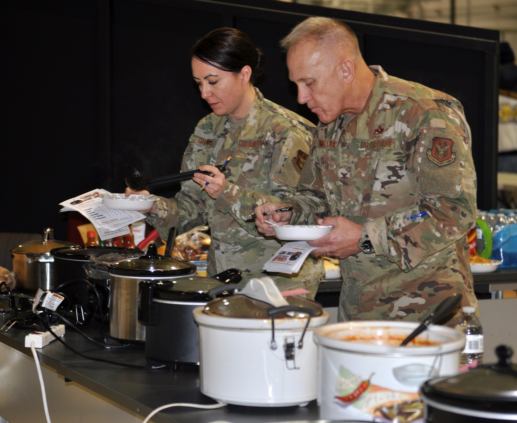 Col. Jay Smeltzer, 445th Maintenance Group commander and Maj. Karen Gharst, 445th Aircraft Maintenance commander, sample various pots of chili while serving as judges for the 445th Airlift Wing’s chili cook-off Dec. 2, 2019.