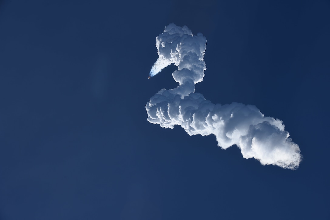 The smoke trail from a rocket is seen against a dark blue sky.