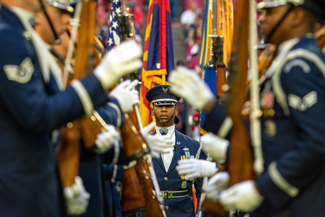 Master Sgt. Jason Prophet, U.S. Air Force Drill Team flight chief, prepares to perform one of the many demonstrations during the halftime show at the Arizona Cardinals Salute to Service football game, Dec. 1, 2019, in Glendale, Ariz. Eight team members hurled their 11-pound weapons over and around Prophet while he walked through their line. In addition to the halftime show, the USAF Drill Team and Color Guard held the flag during the national anthem. (U.S. Air Force photo by Tech. Sgt. Jensen Stidham)