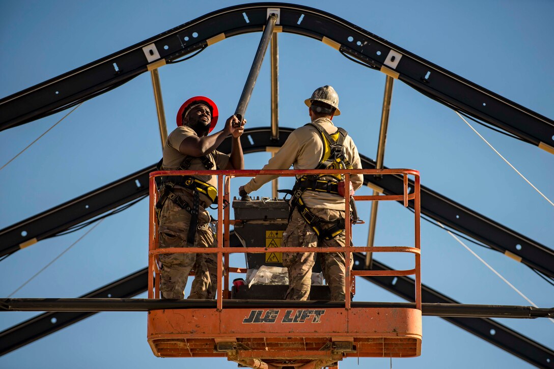 Two airmen work on a lift.