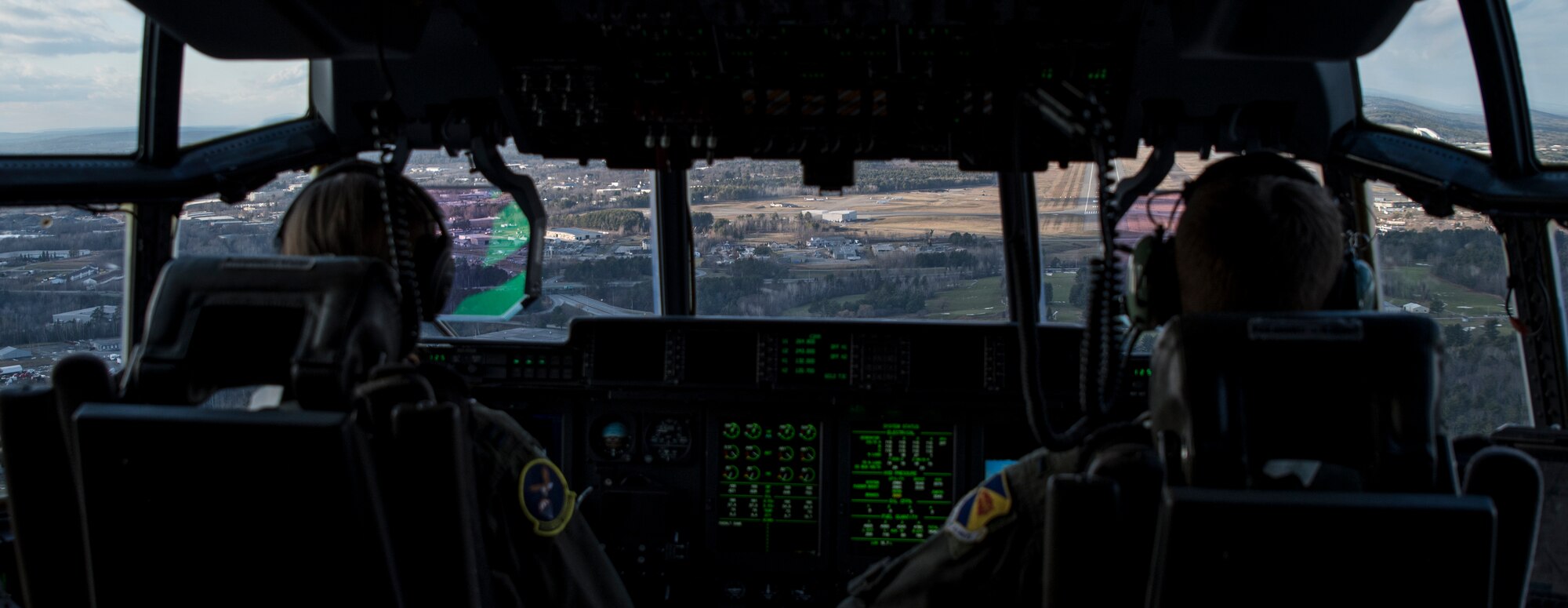 Photo of two military carrier aircraft pilots in a cockpit preparing for landing.