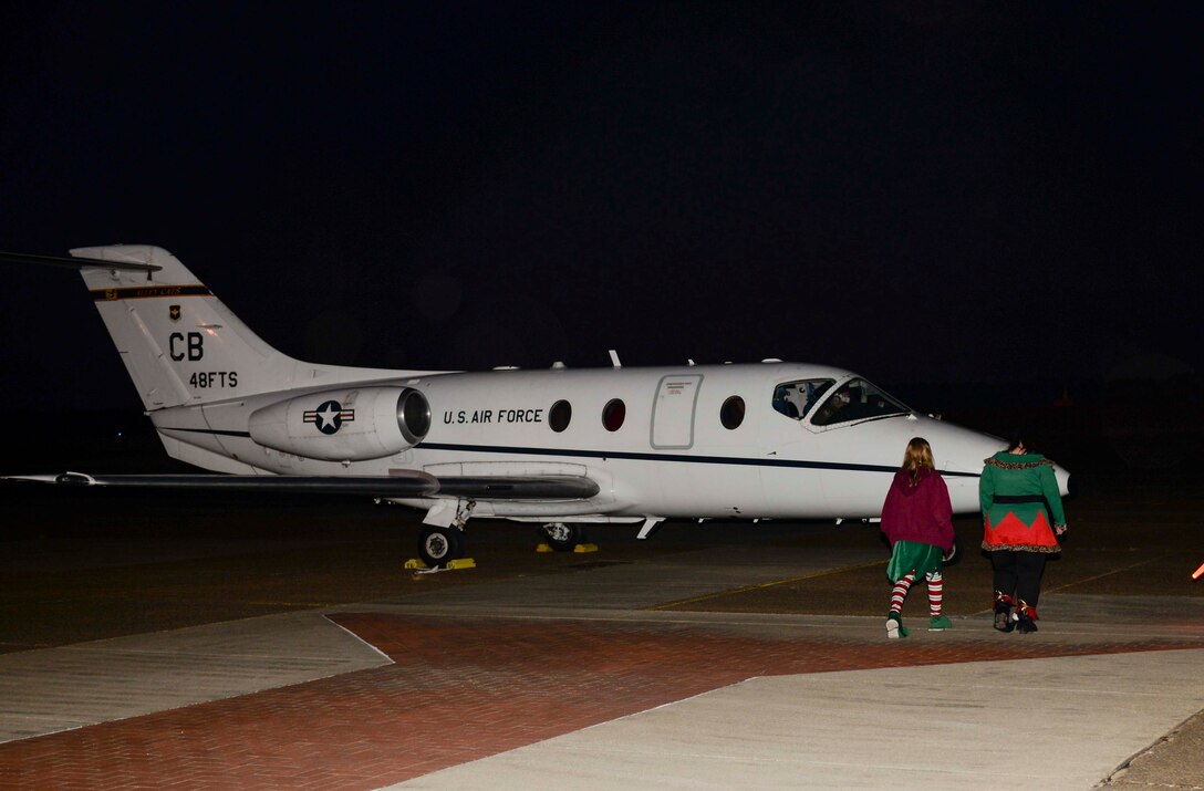 Elves walk toward a T-1 Jayhawk to greet Santa Claus and Mrs. Claus Dec. 3, 2019, at Columbus Air Force Base, Miss. The Clauses landed, then greeted families at the 14th Flying Training Wing Base Operations Center. (U.S. Air Force photo by Airman Davis Donaldson)