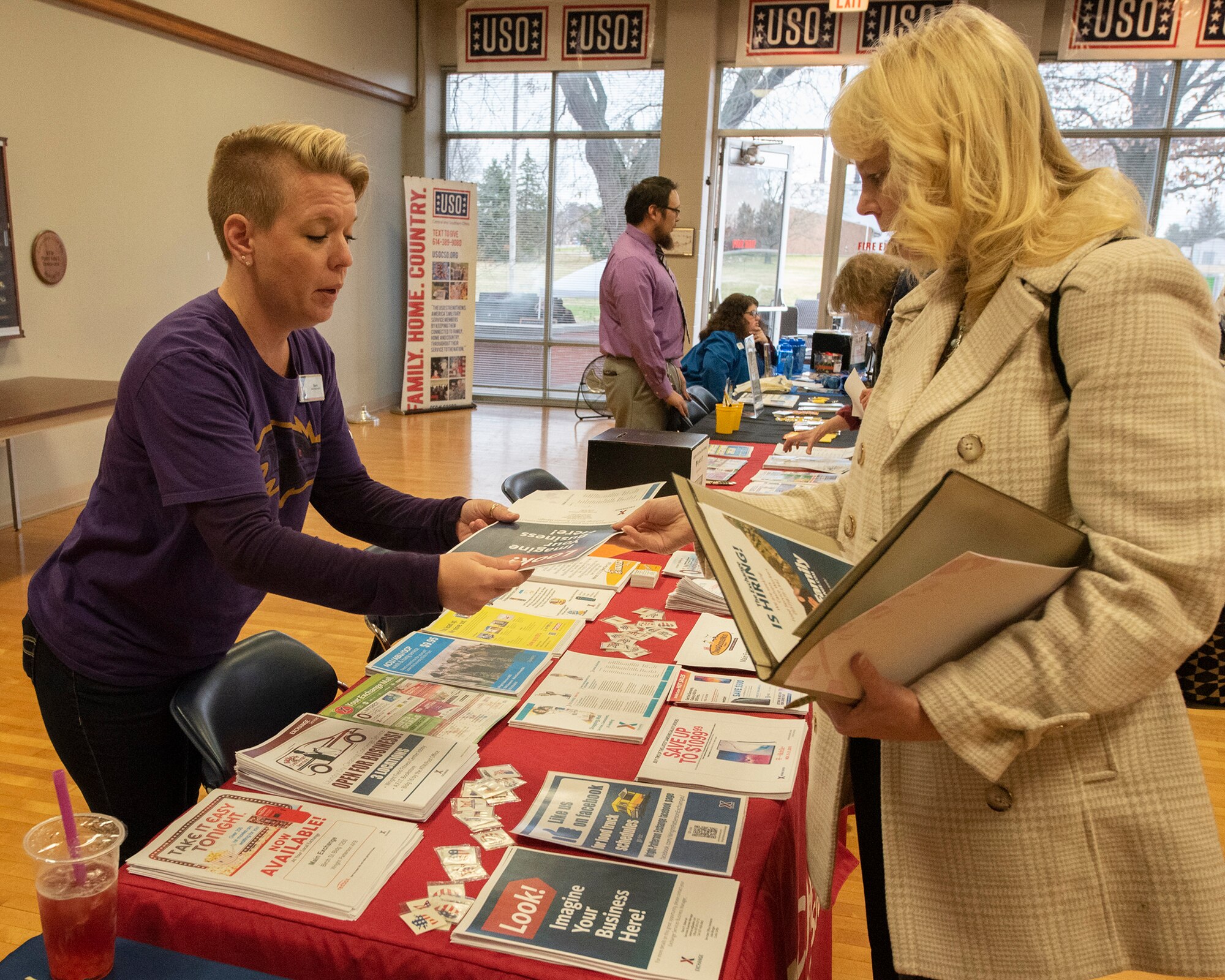 Sara Bateman, Wright-Patt Base Exchange services business manager, shows a brochure to Shannon Carroll, Air Force Research Laboratory, information management lead, during the “ThanksCIVing” Information Fair, hosted by the Affirmative Employment Program, inside the USO building at Wright-Patterson Air Force Base, Ohio, Nov. 21, 2019. Many information booths were set-up to share information about services and benefits available to Air Force civilian employees.  (U.S. Air Force photo by Michelle Gigante)