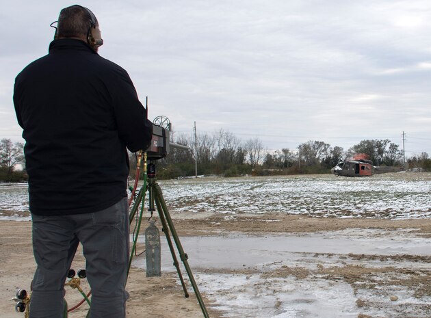 Red Flag-Rescue exercise integration manager Ed Neeley, fires a .50cal machine gun simulator at a helicopter during a demonstration at the National Center for Medical Readiness in Fairborn, Ohio, Nov. 14.  Using sensors to track the fire in the constructive space, an improvised explosive device simulator on the helicopter explodes after sensing the hit. (U.S. Air Force photo/Will Graver)