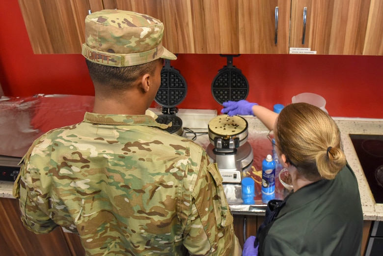 Holly Finneran, USO staff member, instructs U.S. Air Force Airman 1st Class Devin Luckett, 39th Force Support Squadron Patriot Village contingency lodging representative, on how to make waffles during Waffle Wednesday, Nov. 13, 2019, at Incirlik Air Base, Turkey. The Incirlik USO hosts over 30 events a month including free waffles on Wednesday mornings. (U.S. Air Force photo by Staff Sgt. Eric Mann)