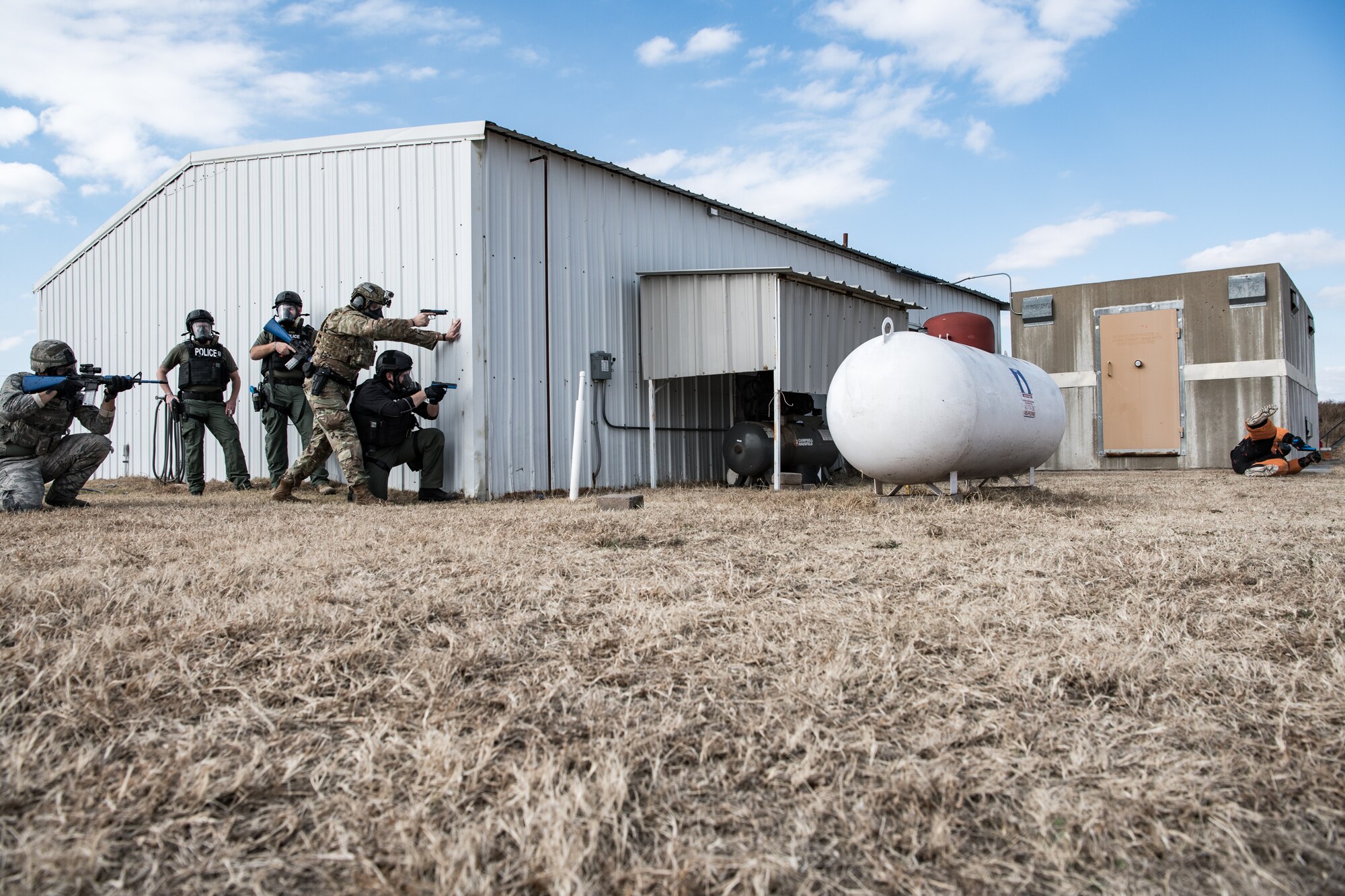 A team of Ardmore Police Department SWAT members and 137th Special Operations Security Forces Squadron Airmen use the end of a building as protection while they simulate engagement with a possible suspect with a gun during SWAT training conducted by the Oklahoma County Sheriff's Office at the OCSO training range in Spencer, Okla., Nov. 4, 2019. (U.S. Air National Guard photo by Staff Sgt. Brigette Waltermire)