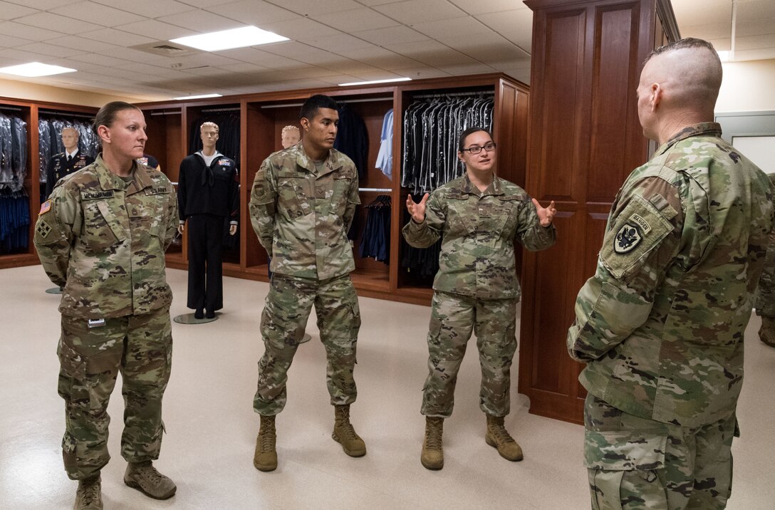 Master Sgt. Naomi Bouska, Air Force Mortuary Affairs Operations  noncommissioned officer in charge of uniforms, briefs Army Command Sgt. Maj. John Wayne Troxell, senior enlisted advisor to the chairman of the Joint Chiefs of Staff, Dec. 3, 2019, during an orientation of the mortuary facility. Troxell thanked Bouska, Sgt. 1st Class Nicole McMinamin and Senior Airman Isai Sorcia for their service in providing dignity, honor and respect to fallen service members. (U.S. Air Force photo by Roland Balik)