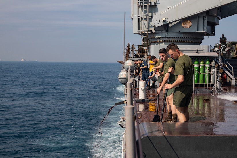 A group of marines and sailors sweep a warship.