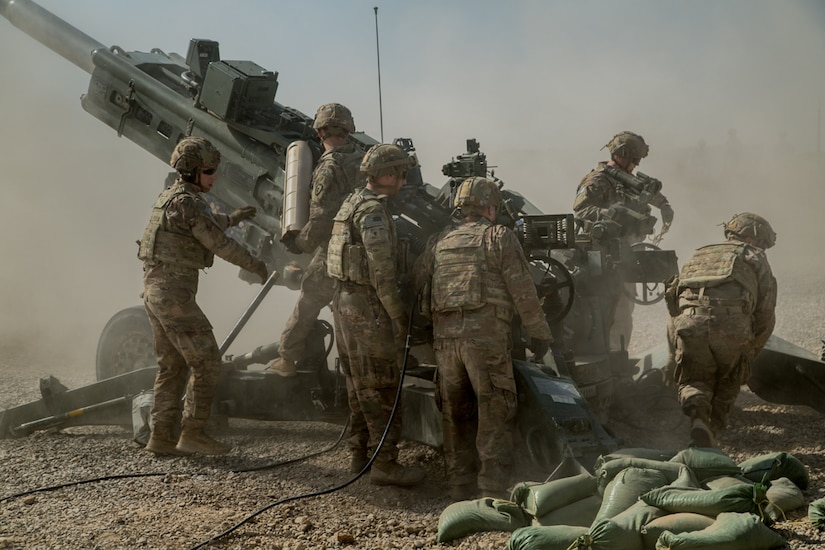 Six soldiers work around a large gun.