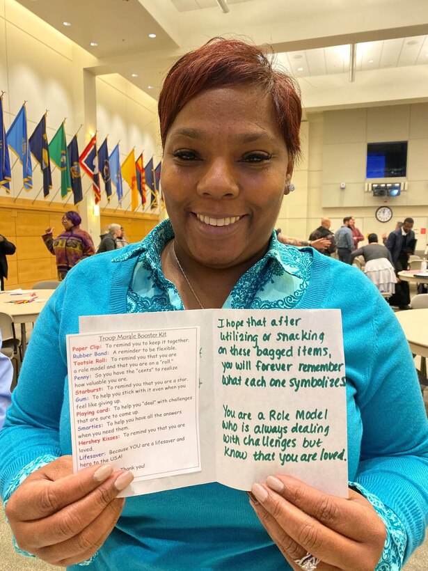 Faylice Jones, a DLA Troop Support Industrial Hardware contracting specialist, poses with one of the cards included in morale and resiliency bags assembled by participants in the Industrial Hardware Success and Partnership in Reaching Excellence mentoring program December 3, 2019, in Philadelphia.