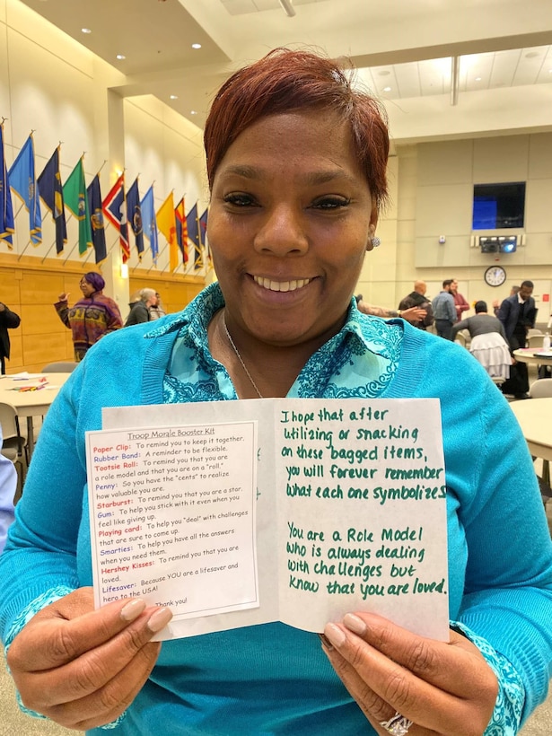 Faylice Jones, a DLA Troop Support Industrial Hardware contracting specialist, poses with one of the cards included in morale and resiliency bags assembled by participants in the Industrial Hardware Success and Partnership in Reaching Excellence mentoring program December 3, 2019, in Philadelphia.