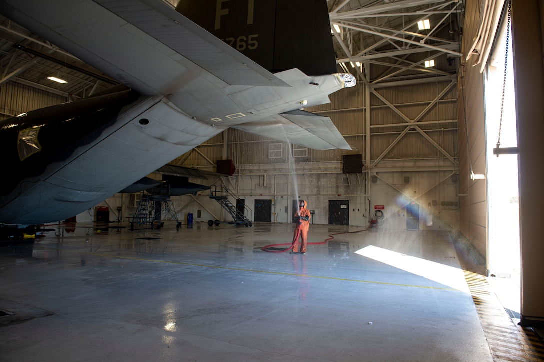 Photo of an Airman spraying the tail fin of an HC-130J Combat King II