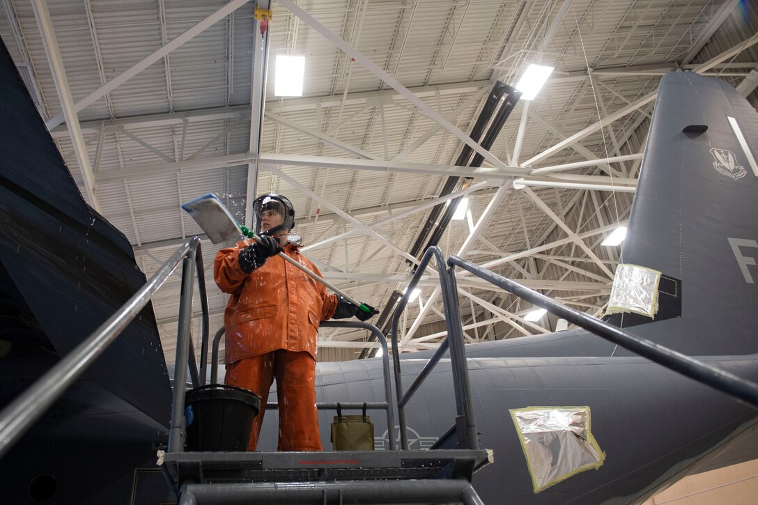 Photo of an Airman using a wash pad to clean the left wing of an HC-130J Combat King II