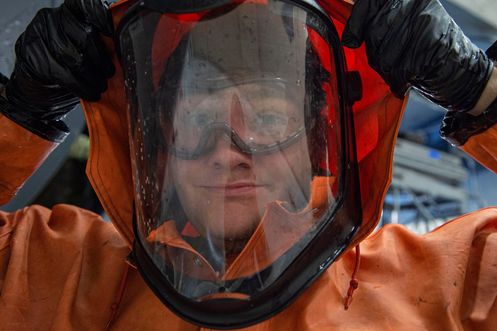 Photo of an Airman putting on a hood of a wash suit during an HC-130J Combat King II wash