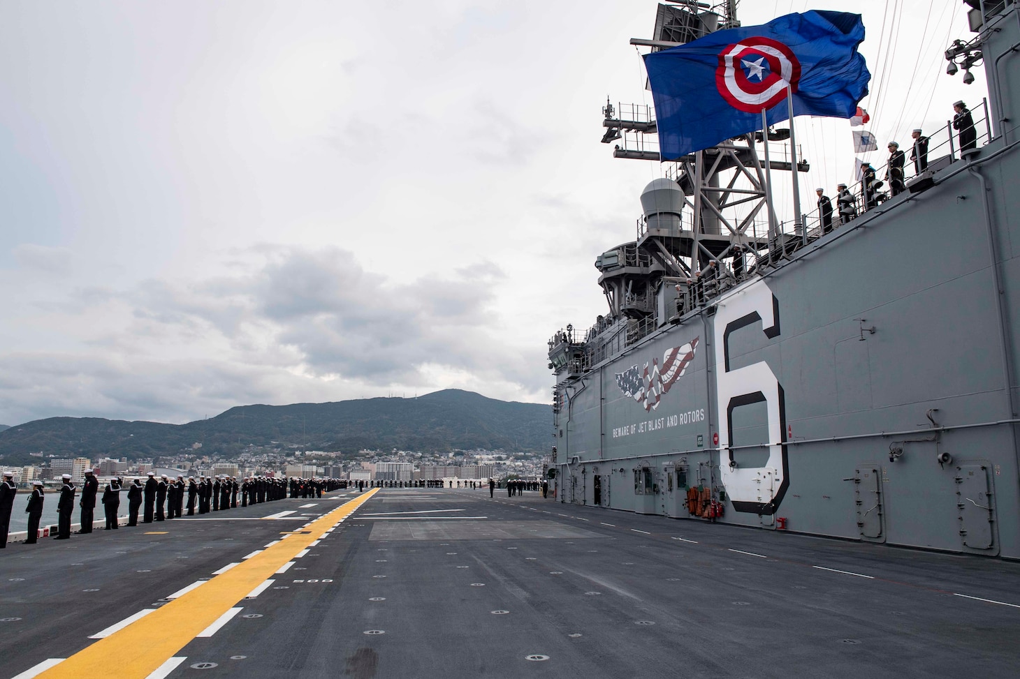 SASEBO, Japan (Dec. 6, 2019) Sailors man the rails as the amphibious assault ship USS America (LHA 6) arrives at Sasebo, Japan to join the forward-deployed naval forces. America is assigned to Amphibious Squadron Eleven and will serve as the flagship for Expeditionary Strike Group 7 while conducting routine operations in the Western Pacific.